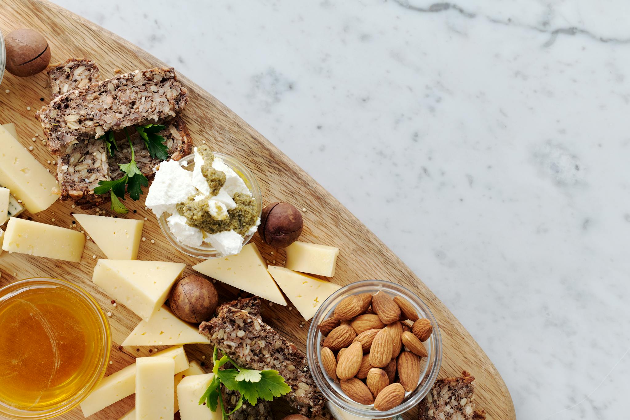 Top view of a gourmet cheeseboard featuring assorted cheeses, almonds, and honey, ideal for a healthy lifestyle.